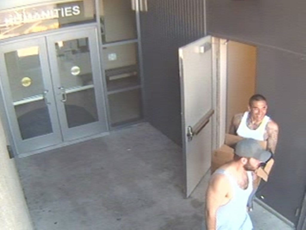 Two burglary suspects are seen exiting the Humanites Building on Saturday, August 16, 2014. The suspect in the white tank-top was reported by Officers of the Cypress Police Department to have been carrying a gun. He is unidentified and remains at large. The suspect wearing the grey baseball-style cap was arrested shortly after this image was captured. He is known to Campus Safety Officers and considered to be dangerous. Anyone who sees either suspect should avoid contact and contact police or Campus Safety when it’s safe to do so. 