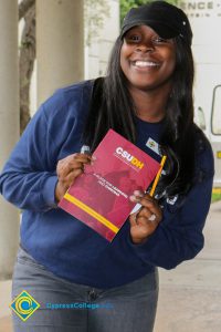 A smiling young woman holding a CSUDH brochure.