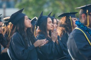 Graduates applauding during commencement.