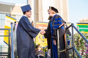 President, JoAnna Schilling shaking a graduates hand.
