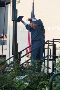Graduate holding diploma and celebrating.
