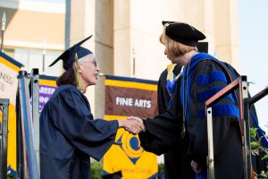 President, JoAnna Schilling shaking a graduates hand.