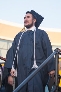 Graduate standing and smiling.