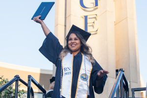 Graduate holding diploma in the air.