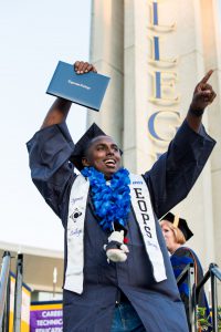 Graduate pointing and holding up diploma.