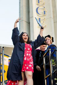 Graduate celebrating, holding up two fingers.