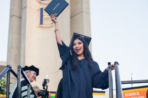 Graduate holding up diploma.