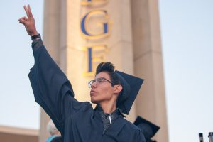 Graduate holding up two fingers.