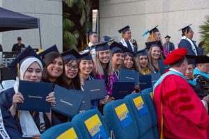 Smiling students holding degrees during commencement