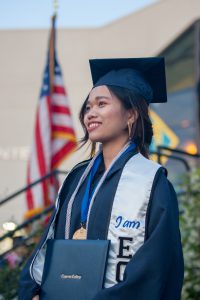 Female student in cap and gown holding degree