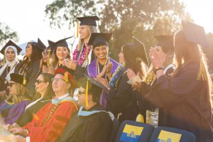 Graduates applauding during commencement.