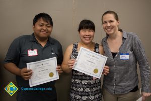 Two women and a young man holding awards.