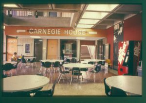Vintage photo shows tables and chairs and a soda machine in Carnegie House which was the common gathering place for students.