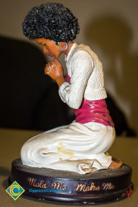 Ceramic statue with woman kneeling and praying.