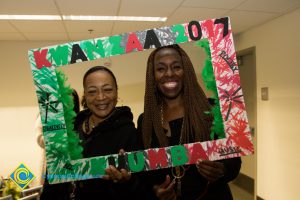 Two smiling women holding Kwanzaa 2017 frame.