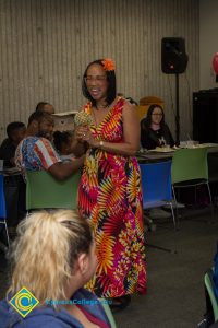 Woman in a colorful long dress and orange flower in her hair smiling.