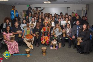 Staff and students smiling holding African drums.