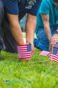 Two gentlemen placing flags on the campus lawn