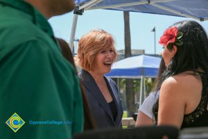 President JoAnna Schilling talking to a woman with a flower in her hair.