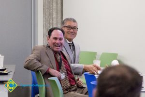 Two men in suits laughing.