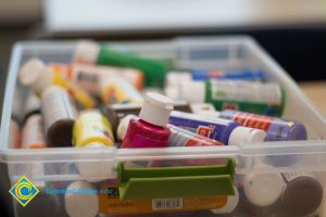 Container full of paint bottles.