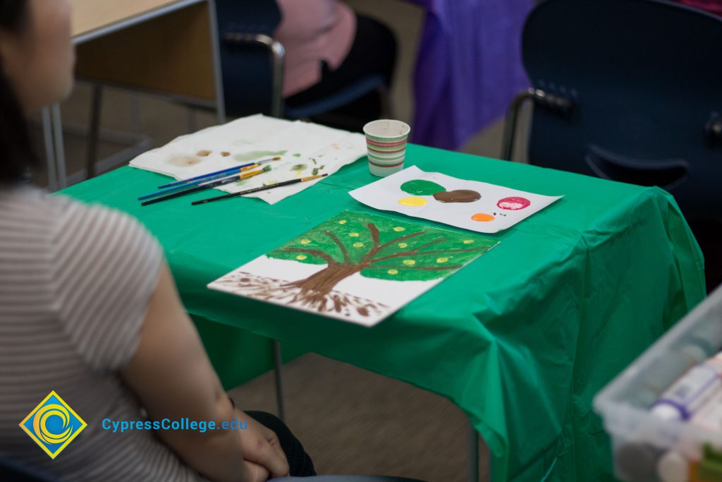 Table with paintbrushes and painted tree.