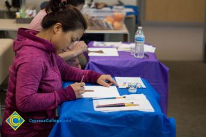 Woman sitting at a table and painting a picture.