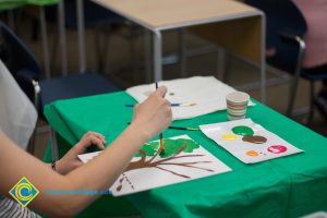 Woman sitting at a table and painting a picture.