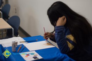 Woman sitting at a table and painting a picture.