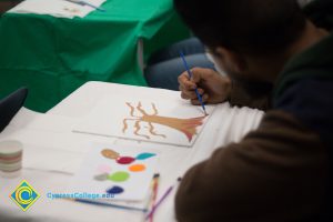 Woman sitting at a table and painting a picture.