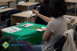 Woman sitting at a table and painting a picture.