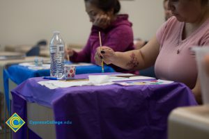 Woman sitting at a table and painting a picture.