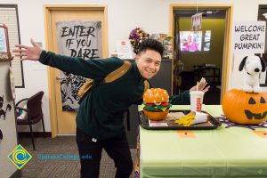 Student with arms out next to a tray of fake burger, fries and drink