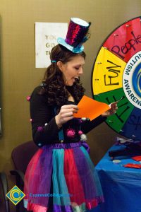 Woman smiling with hat and skirt standing next to wheel