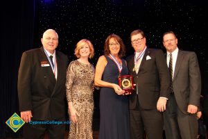 Dr. JoAnna Schilling with a woman holding an award and three men in suits and tie.