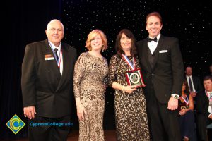 Dr. JoAnna Schilling with a woman holding an award and two men in suits.