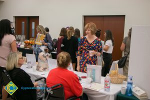 Dr. JoAnna Schilling at the West Orange County Women's Conference talking to two women at a booth table.