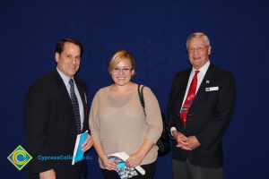 Scholarship recipient with two men in suits and tie.