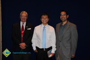 Two men in suits with a young man in a white shirt and blue tie.