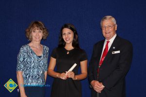 A young woman in a black dress with a woman in a blue print shirt and a gentleman in a black suit and red tie.