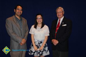 Two men in suits with a young lady who is a scholarship recipient.