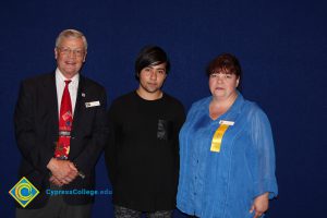 Scholarship recipient with a man in suit and red tie and Lynette Young.