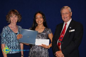 Student showing her scholarship award with a woman in a blue print shirt and a gentleman in a black suit and red tie.