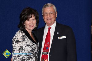 Lynn Mitts with a gentleman in a black suit and red tie.