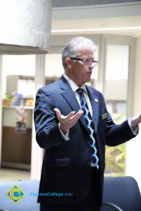 President Bob Simpson in a blue suit and tie with hands out.