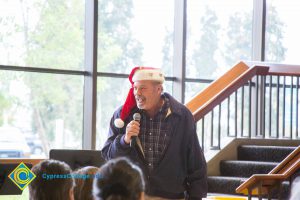 A man in a Santa hat speaking into a microphone.