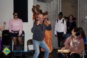 Employees and students dressed up for and participating in Mardi Gras parade, while Professor Emeritus Mark Majarian dances