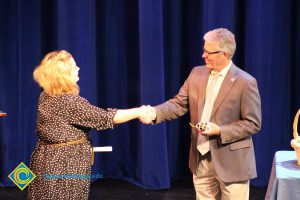 President Bob Simpson shaking hands with a woman in a brown polka dot dress.