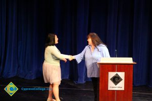 A student being congratulated as she receives her award at the 2014 Scholarship Awards Ceremony.