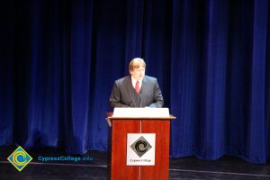 A man in a suit and red tie speaking at the 2014 Scholarship Awards Ceremony.